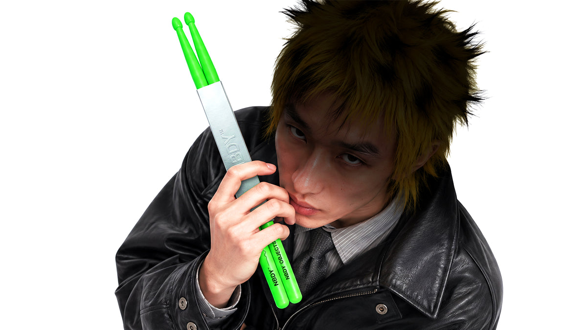 Model holding a pair of NBDY drumsticks to his face