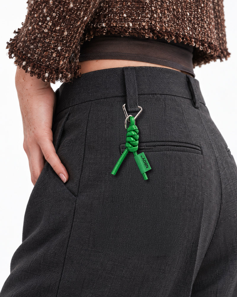 Green NBDY keychain clipped to the belt loop of grey trousers