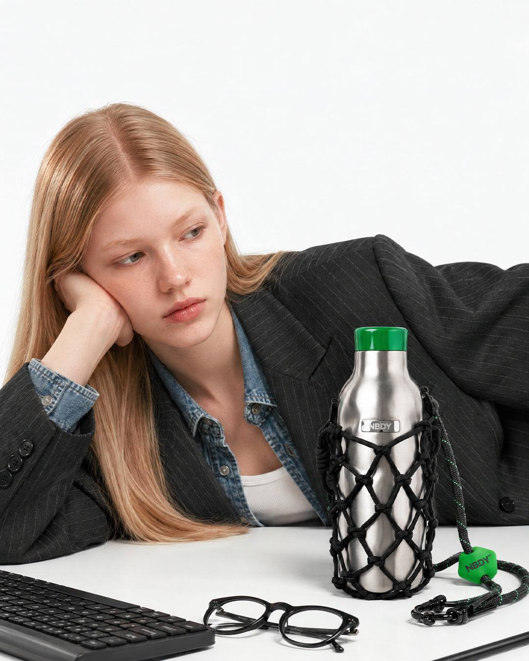 Model at a desk beside the NBDY tumbler in its knotted net holder
